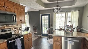 A modern kitchen with wooden cabinets, a built-in microwave, stainless steel appliances, and a large island with a dishwasher.