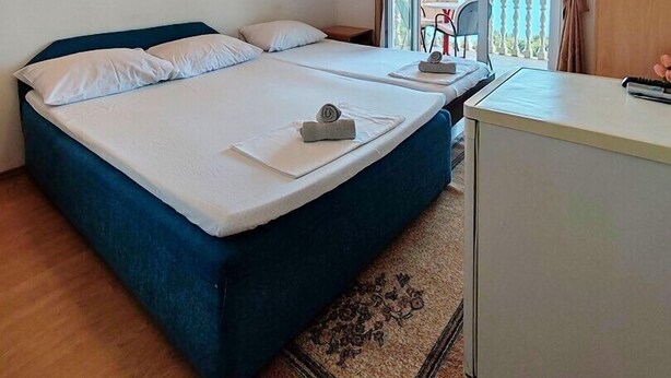 Een tweepersoonsbed met een blauw hoofdeinde, een klein bureau en uitzicht op de omgeving.