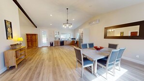 A spacious kitchen with wooden flooring, a dining area with a large table and chairs, and a kitchen counter with appliances.