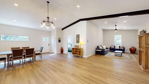 A spacious living area with a dining table and chairs, a sofa set, and a wooden cabinet.