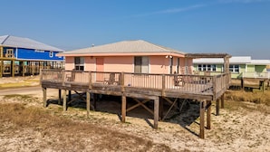A beachfront house with a wooden deck and a small porch, surrounded by sand and sparse vegetation. - Gulf Beachside 2 Bedroom, 1 Bath, Pet Friendly, Adorable! (Dauphin Island)