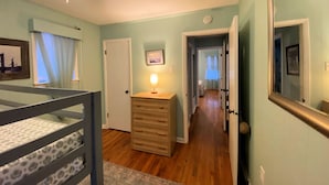 A bedroom with a bunk bed, a dresser, a ceiling fan, and a hallway leading to another room. - Gulf Beachside 2 Bedroom, 1 Bath, Pet Friendly, Adorable! (Dauphin Island)