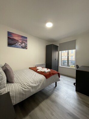 Ein Schlafzimmer mit Bett, Fenster mit Blick, einem Bild an der Wand und einem Kleiderschrank.