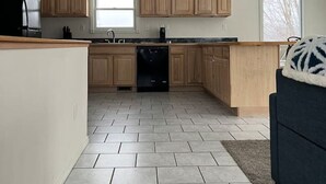Een moderne keuken met lichte houten kastjes, een zwarte koelkast en een vaatwasser.