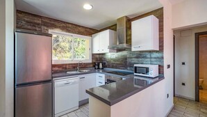 A modern kitchen with stainless steel appliances, white cabinetry, and a large window providing natural light. - Villa Pomera Dos by Villa Plus (Beniarbeig)