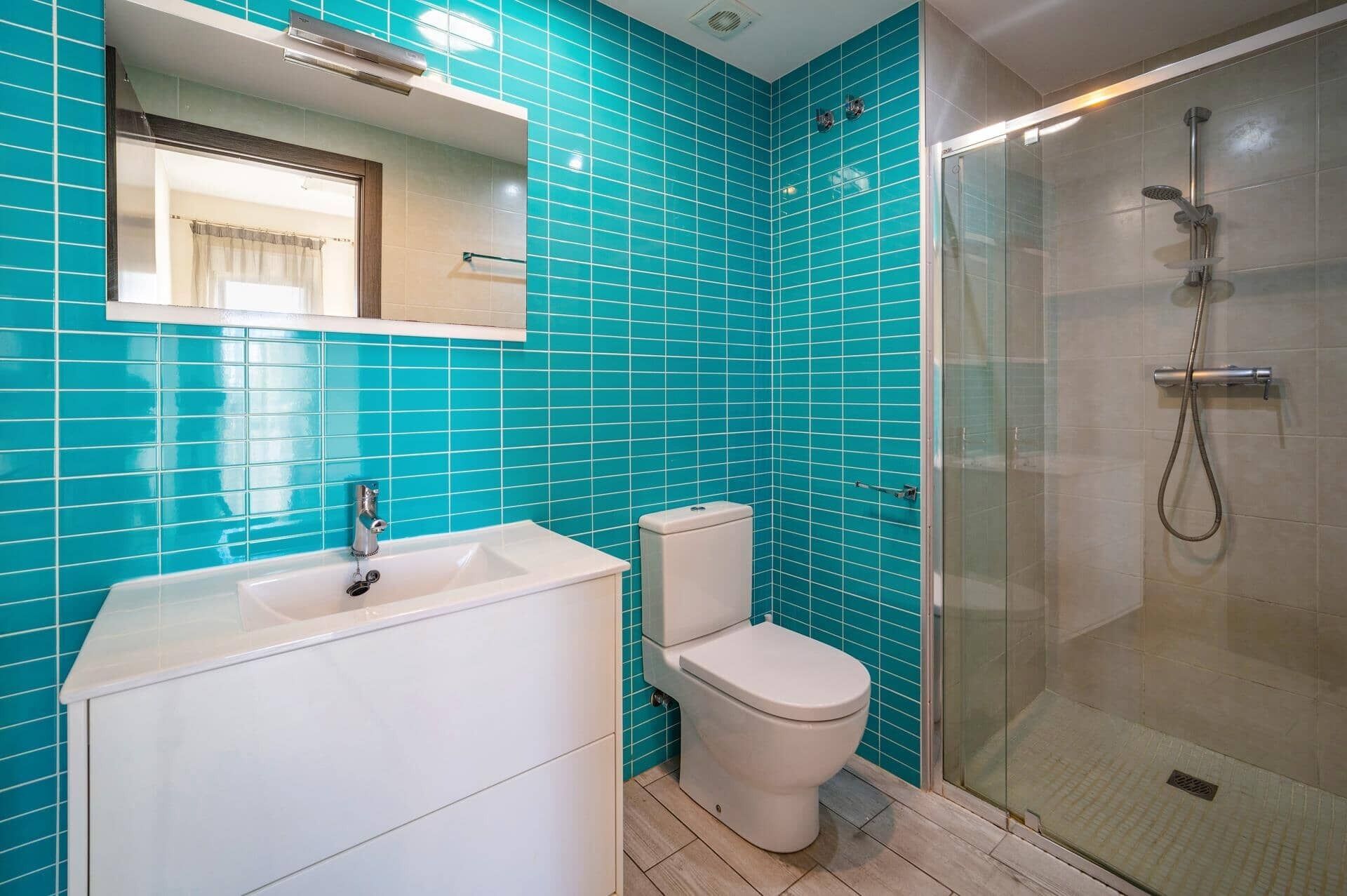 A bathroom with a white sink, toilet, and glass-enclosed shower.