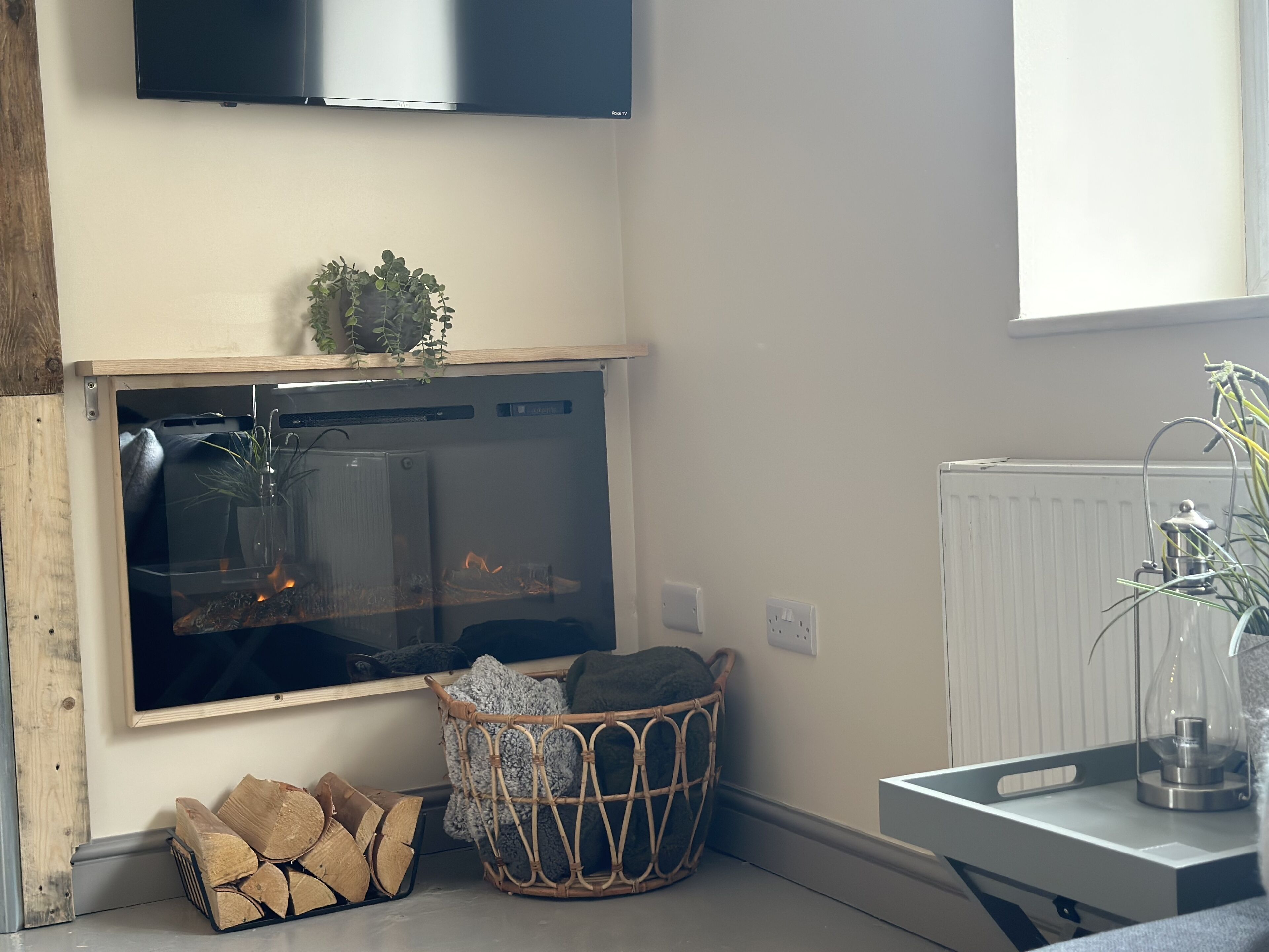 Een moderne keuken met een ingebouwde open haard, een groot raam en een houten kast boven de open haard.