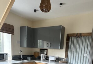A kitchen with grey cabinets, a microwave, a kettle, and a toaster. - Charming 1-bed Apartment in Hereford (Hereford)