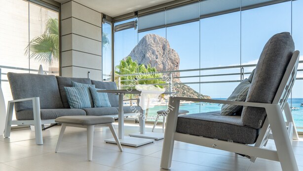 A modern lounge with a sofa, armchair, and coffee table, large windows with a view of the sea and a mountain, and a balcony with plants. - CostaBlancaDreams - Bauprés in Calpe (Calpe)