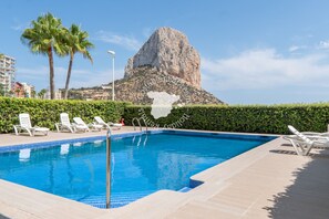 A swimming pool with lounge chairs, palm trees, and a mountain in the background. - CostaBlancaDreams - Bauprés in Calpe (Calpe)