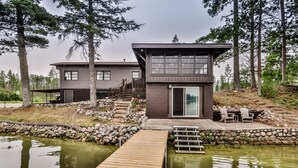 Ein modernes, zweistöckiges Haus mit einem Steinweg, der zu einem Steg über einem Teich führt.