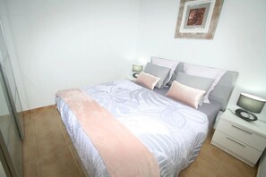 Restful retreat with a neatly made bed and a bedside table featuring a lamp and decorative item.