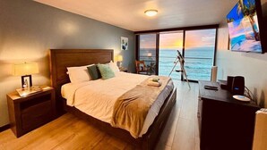 Un dormitorio con una cama grande, un escritorio, un telescopio y vistas al océano.