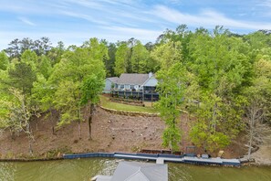A house surrounded by dense trees, with a dock extending into a body of water.