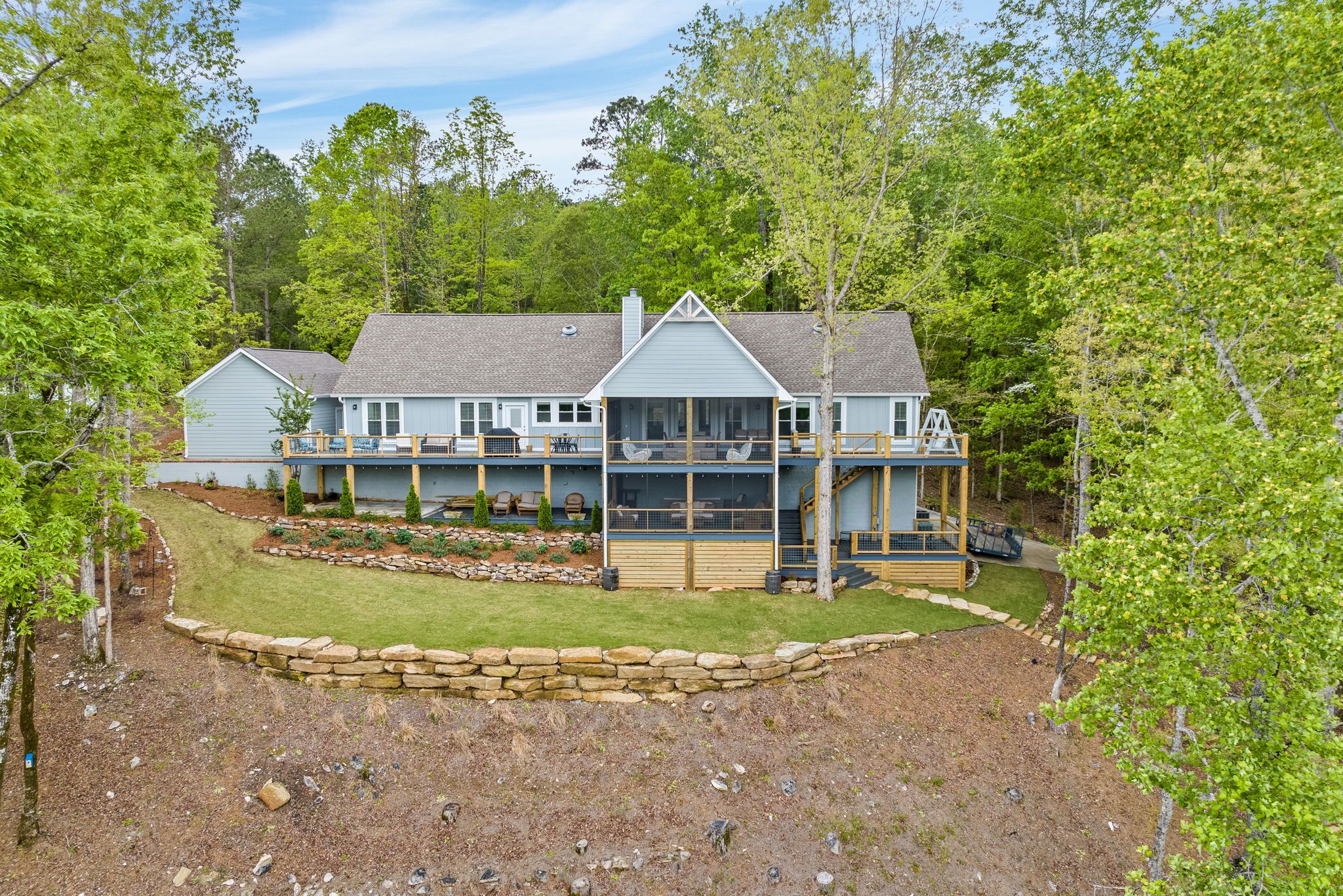 A large, two-story house with a covered porch and a stone retaining wall.