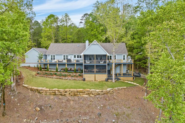 A large, two-story house with a covered porch and a stone retaining wall.
