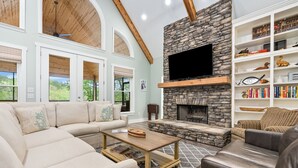 Un salón espacioso con chimenea de piedra, un televisor de pantalla plana grande y una zona de estar acogedora.