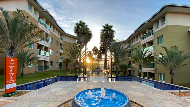 A hotel courtyard with a central fountain, palm trees, and a pool.