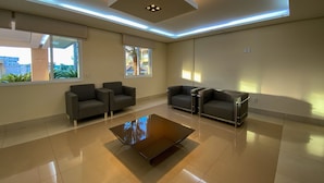 A modern waiting area with a glass coffee table, two sofas, and a ceiling light fixture.