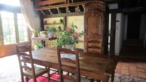 A dining area with a wooden table and chairs, surrounded by potted plants and a red carpet. - Gîte de Charme en Pleine Nature (Champcevinel)