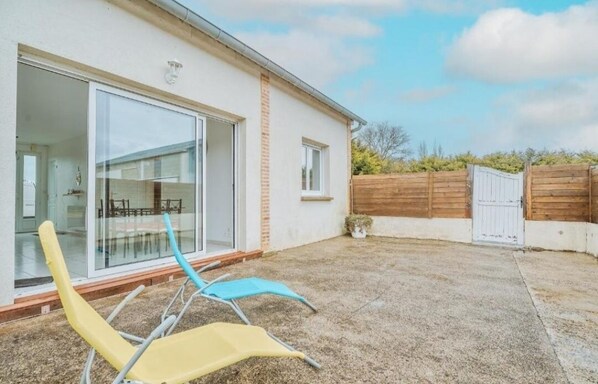 A modern house with a glass door leading to a patio area.