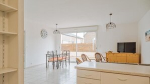 Una cocina amplia con una isla grande, un comedor con sillas y un televisor sobre un mueble de madera.