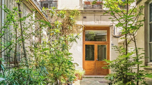 A narrow stone pathway leading to a wooden door, flanked by lush greenery and potted plants. - Le Marais - Les Halles Colorful & Modern 3BD (Paris)