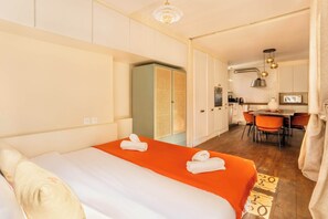 A hotel room with a bed, a small kitchenette, and a dining area.