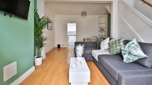 Una sala moderna con un sofá gris, una mesa de centro blanca y una planta grande en maceta.