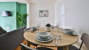 Un comedor con una mesa redonda, sillas y una pared verde con un televisor.
