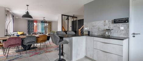 Una cocina moderna con una isla integrada, gabinetes grises y un lavamanos de acero inoxidable.