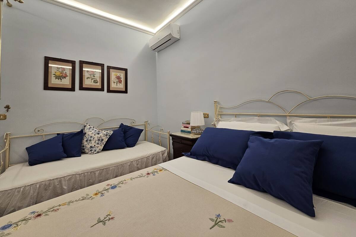Un dormitorio con dos camas, una mesita de noche y tres cuadros enmarcados en la pared.