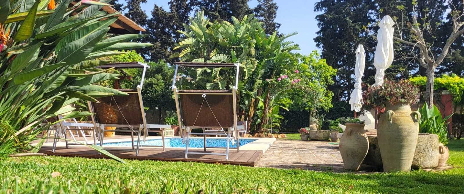 A pool area with two swing chairs, a small pool, and potted plants.