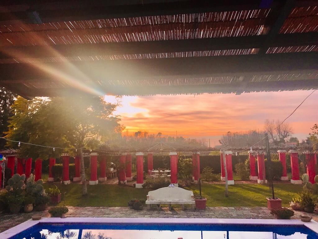 A poolside view with a sunset, red pillars, and a white bench.