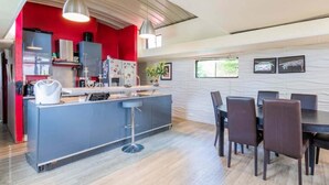 Een moderne keuken met een centraal eiland, barkrukken en een eethoek met een tafel en stoelen.