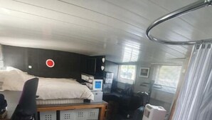 Een kleine slaapkamer met een bed, bureau, computer en ligbad.