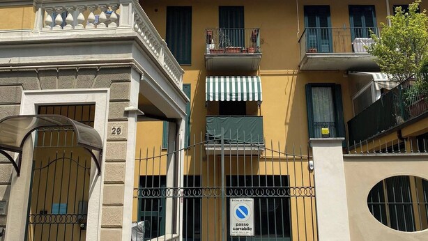 Un edificio giallo con un ingresso chiuso da cancello, diversi balconi e un cartello che indica divieto di parcheggio.