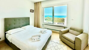 A hotel room with a bed, a chair, a window with a view of the sea, and a radiator. - Villa Neptune Pour 8 Pieds Dans l eau Carthage (Carthage)