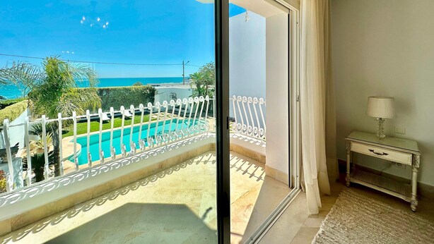 A balcony with a pool view, a white console table, and a lamp. - Villa Neptune Pour 8 Pieds Dans l eau Carthage (Carthage)