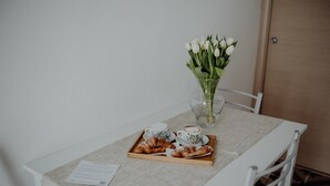 A table with a tray of pastries, two cups of coffee, and a vase of white flowers. - Casa Viola - Palazzo Pezzola (Monopoli)