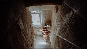 A narrow staircase with stone walls, a metal handrail, and a small table with a telephone and a cup. - Casa Viola - Palazzo Pezzola (Monopoli)