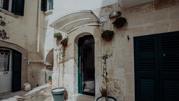 A narrow street with stone buildings, potted plants, and a visible door number 47. - Casa Viola - Palazzo Pezzola (Monopoli)