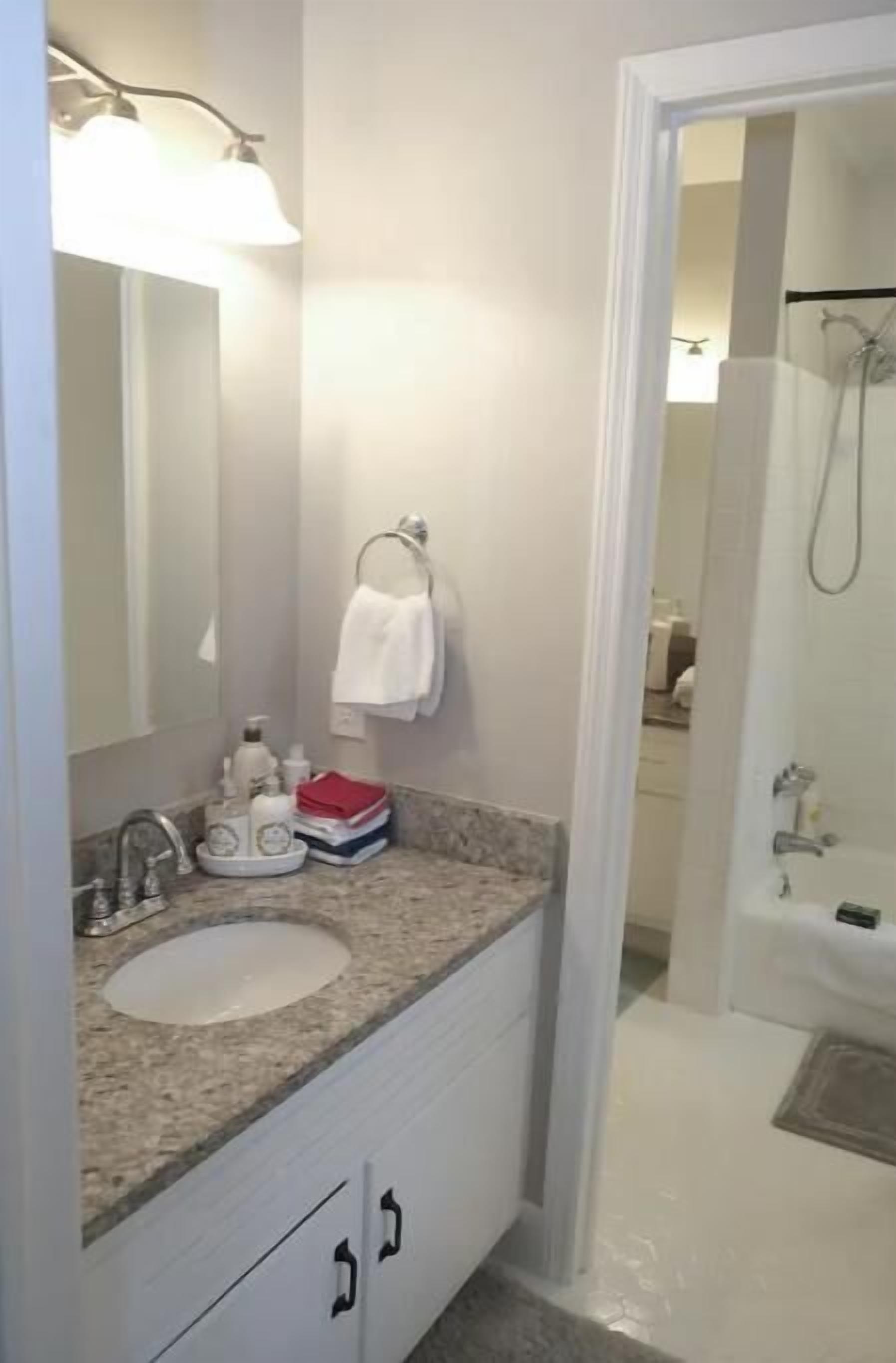 Un baño con lavabo, espejo y perchero para toallas.