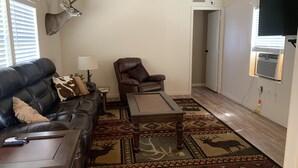 A living room with a leather sofa, a brown leather chair, a wooden coffee table, and a patterned rug.