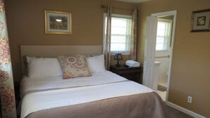 Un dormitorio con cama, mesita de noche, ventana y puerta.