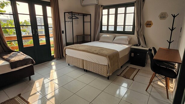 A bedroom with a bed, a desk, a chair, a coat rack, and a wardrobe. - Pousada Makani Kai (Florianópolis)