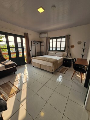 Un dormitorio con cama, escritorio, silla, perchero y armario.