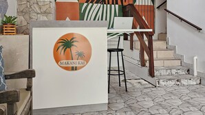 A reception area with a logo, a staircase, and a stone wall. - Pousada Makani Kai (Florianópolis)