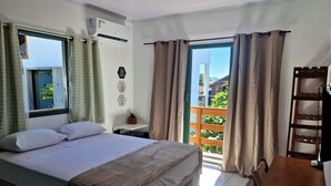 A bedroom with a bed, a desk, a chair, a window, and a view of the outside. - Pousada Makani Kai (Florianópolis)