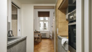 Une cuisine étroite avec un coin repas, une fenêtre et un radiateur.